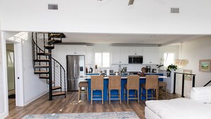 A modern kitchen with white cabinets, a blue island, and a stainless steel refrigerator.