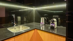 Eine moderne Küche mit schwarzem Arbeitsplatz, Spüle aus Edelstahl und einer Kaffeemaschine.