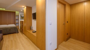 Ein Schlafzimmer mit einem Bett, einem Holzschrank und einem an der Wand befestigten Fernseher.