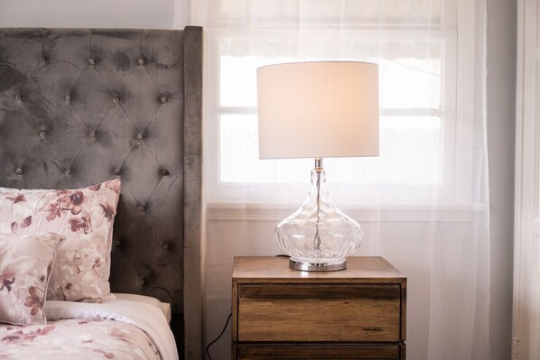 Une chambre à coucher avec une tête de lit capitonnée, une lampe de chevet et une table de chevet en bois.