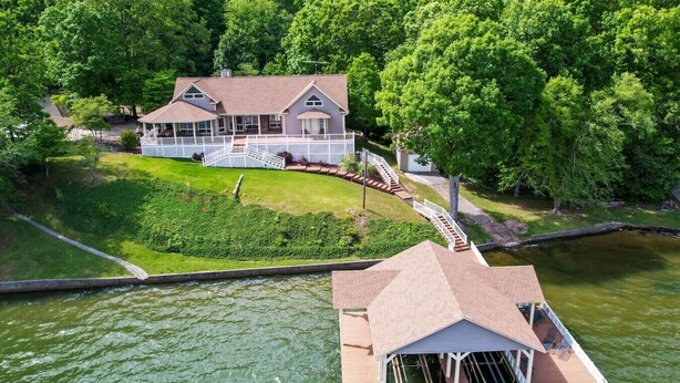 A house with a dock extending into a river, surrounded by lush greenery. - The View on Weiss Lake (cedar bluff)