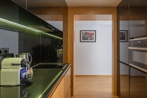 A modern kitchen with a built-in espresso machine, a stainless steel stove, and wooden cabinetry.
