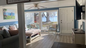 Ein gemütliches Zimmer mit Bett, Sessel, Fernseher und Blick ins Freie.