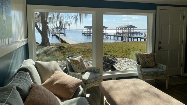 Ein Zimmer mit Blick auf einen Steg und Wasser, eine Couch und zwei Sessel.