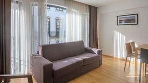A modern living room with a sofa, a dining table with chairs, and large windows with sheer curtains. - Northern Star - Apartment 2.0 Porto (in the city center) (Porto)