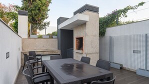 An outdoor patio with a rectangular table and chairs, a brick oven, and a stone wall. - Northern Star - Apartment 2.0 Porto (in the city center) (Porto)