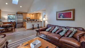 A spacious living area with a leather sofa, wooden dining table, and a kitchen in the background. - 61MBR - Hot Tub - Wi-Fi - Pets Ok - Sleeps 6 (Deming)