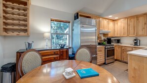 A modern kitchen with wooden cabinets, stainless steel appliances, and a dining area with a table and chairs. - 61MBR - Hot Tub - Wi-Fi - Pets Ok - Sleeps 6 (Deming)