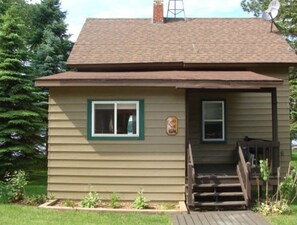 Une maison de plain-pied avec un porche à l’avant, une cheminée et une antenne parabolique.