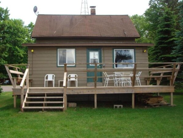 Une petite cabane dotée d’une terrasse, d’une antenne parabolique et d’une cheminée.