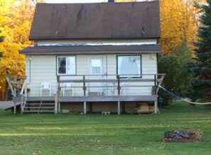Une maison à deux étages avec un porche à l’avant et une petite terrasse.