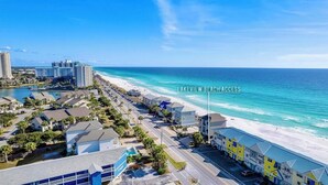 A coastal hotel with a beach access sign, beachfront view, and a parking area. - Clean & Ready for Guests! Recently Remodeled, Steps to the Beach! (Miramar Beach)