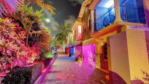 Vista noturna de uma rua ladeada por edifícios iluminados com luzes coloridas.