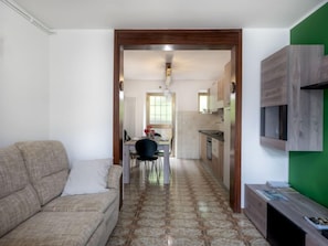 A narrow hallway with a sofa and a dining area at the end.