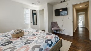 A bedroom with a bed, a ceiling fan, a TV mounted on the wall, and a hallway leading to another room. - 5min-Grant park|Fenced Yard|Parking|Fire Pit&BBQ (Atlanta)