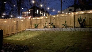 A backyard with a wooden fence, string lights, and potted plants. - 5min-Grant park|Fenced Yard|Parking|Fire Pit&BBQ (Atlanta)