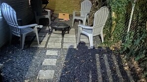 A patio area with white plastic chairs, a small round table, and a cardboard box. - 5min-Grant park|Fenced Yard|Parking|Fire Pit&BBQ (Atlanta)