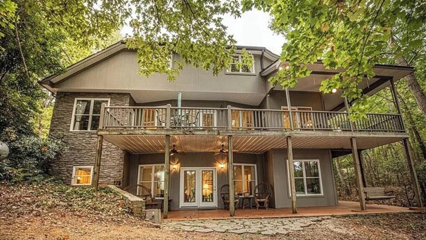 A two-story house with a balcony, stone foundation, and a porch area with seating. - Lake Hartwell Retreat, Clemson Football Weekends, 4BR + Private Dock (Westminster)