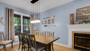A dining room with a wooden table and chairs, a fireplace, and a view of trees through a window. - Lake Hartwell Retreat, Clemson Football Weekends, 4BR + Private Dock (Westminster)