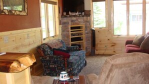A cozy cabin interior with a stone fireplace, wooden walls, and a comfortable seating area. - On North Twin Lake- Northern Exposure Rentals "Musky Lodge" (Phelps)
