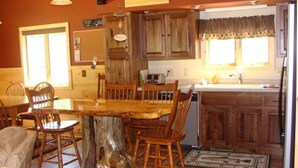 A rustic kitchen with wooden cabinets, a central island with chairs, and a vintage radio. - On North Twin Lake- Northern Exposure Rentals "Musky Lodge" (Phelps)