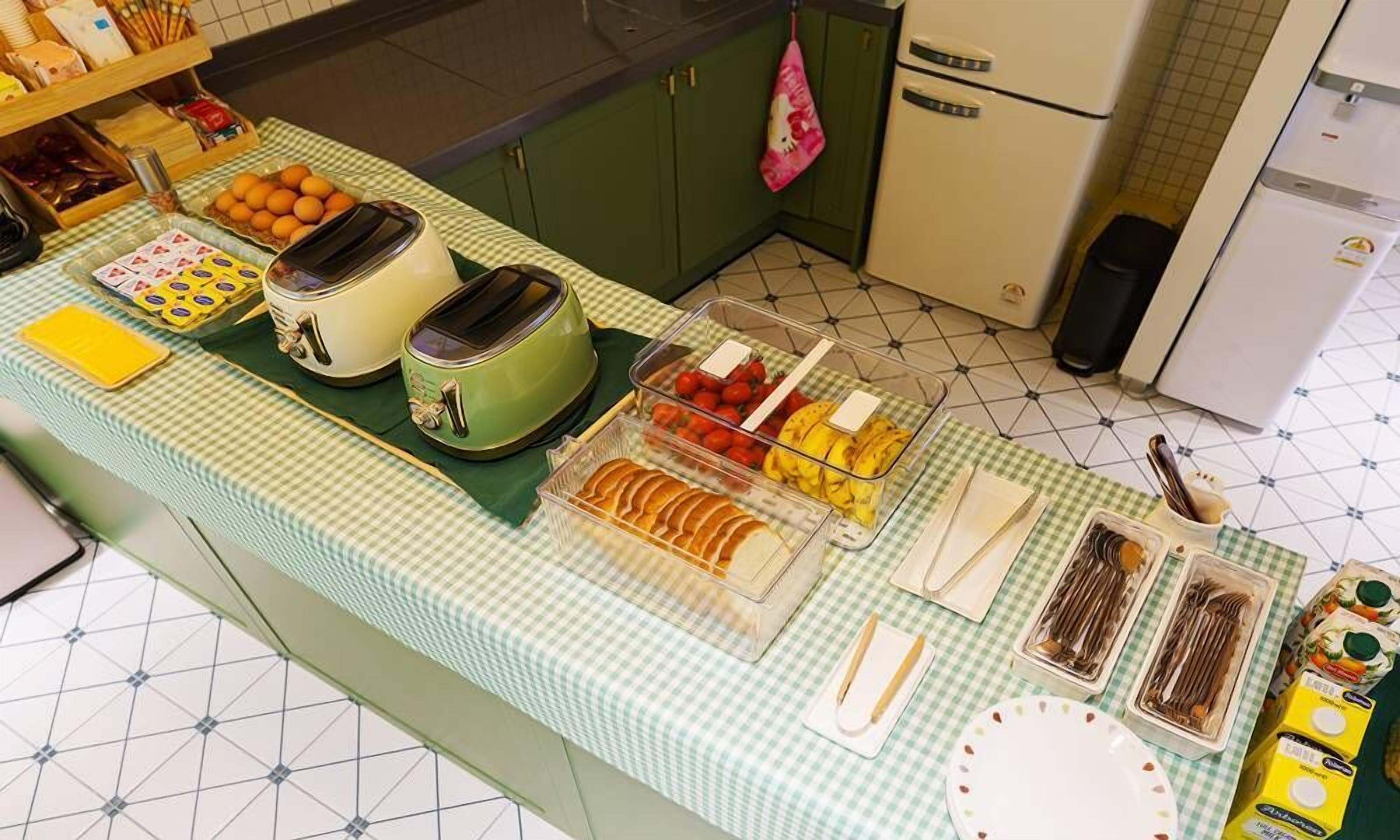 A breakfast buffet with various food items and utensils on a checkered tablecloth.