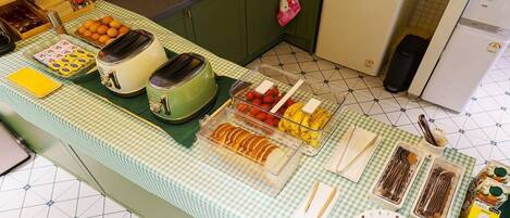 A breakfast buffet with various food items and utensils on a checkered tablecloth.