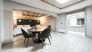 A modern hotel room with a large bed, a dining area with a round table and chairs, and a separate bathroom area with a mirror and sink. - Gumi Time Hotel (Gumi)