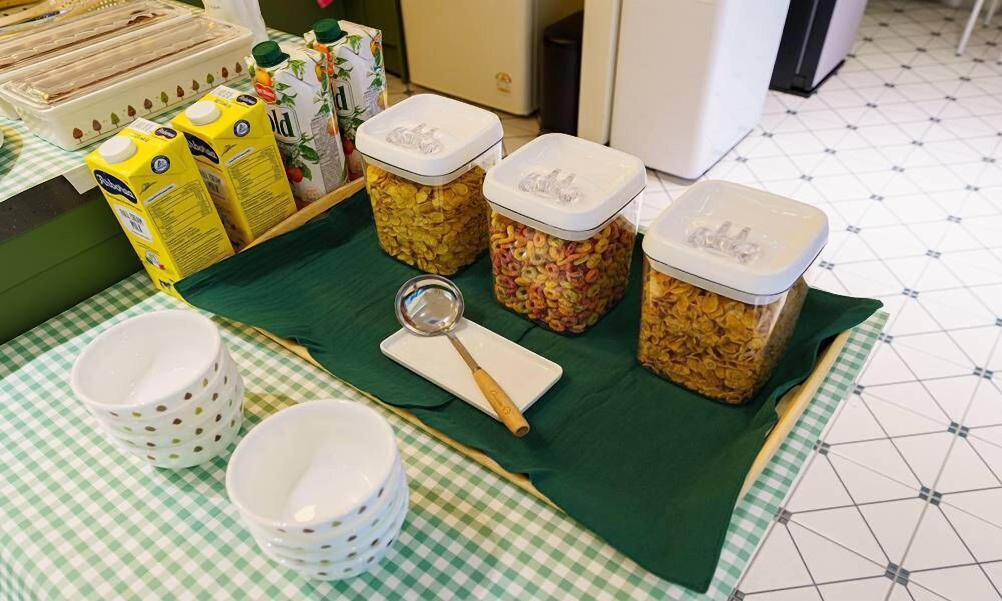 Una mesa de desayuno con cereal, cartones de leche y tazones sobre un mantel a cuadros.