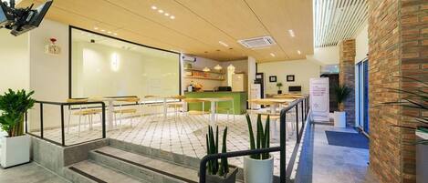 A modern interior with a reception desk, seating area, and a staircase leading to an upper level.