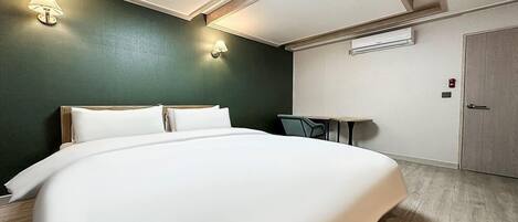 A hotel room with a large bed, a small table, and two wall-mounted lamps.