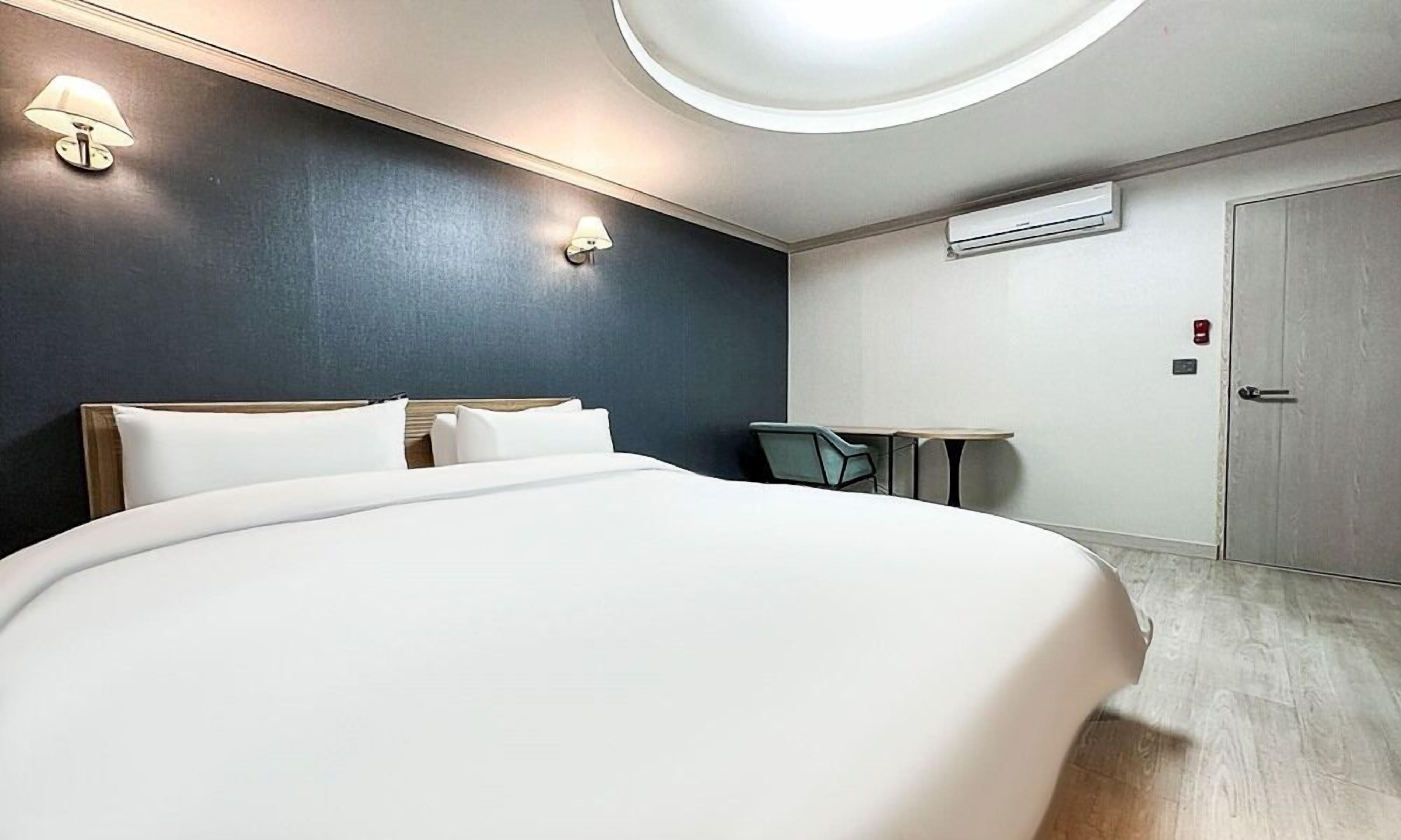 Una habitación de hotel moderna con una cama grande, un escritorio y una silla.