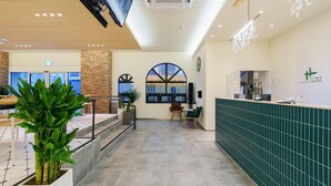 A hotel reception area with a modern design, including a reception desk, a large arched window, and a staircase leading to another floor. - Gumi Time Hotel (Gumi)