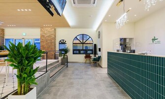A hotel reception area with a modern design, including a reception desk, a large arched window, and a staircase leading to another floor.