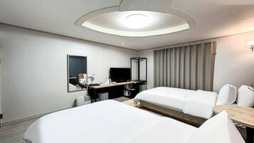 A hotel room with two beds, a desk with a chair, a TV, and a large mirror.