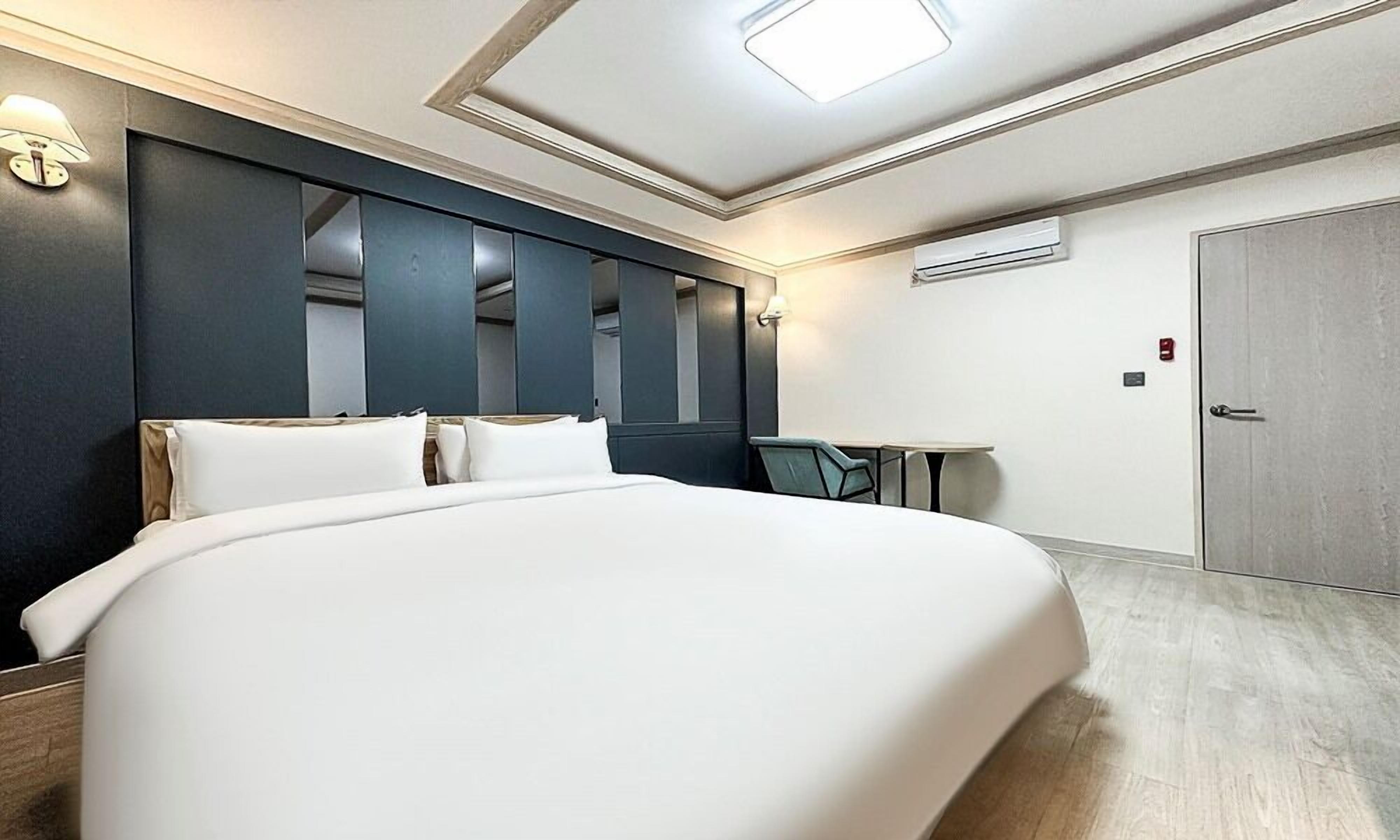 Ein modernes Hotelzimmer mit einem großen Bett, einem kleinen Tisch und einem Kleiderschrank.