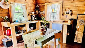 A cozy cabin-style kitchen with wooden walls, a dining table with chairs, and a small refrigerator. - Wood Cabin in the Smoky Mountains (Sevierville)