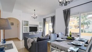 A modern living room with a sofa, dining table, and TV. - 15 Noria Azul Sunny apartment, terrace wifi (La Cala de Mijas)