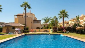 A swimming pool surrounded by palm trees and a building with a tiled roof. - 15 Noria Azul Sunny apartment, terrace wifi (La Cala de Mijas)