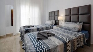 A hotel room with two beds, a chandelier, and a large window with curtains. - 15 Noria Azul Sunny apartment, terrace wifi (La Cala de Mijas)