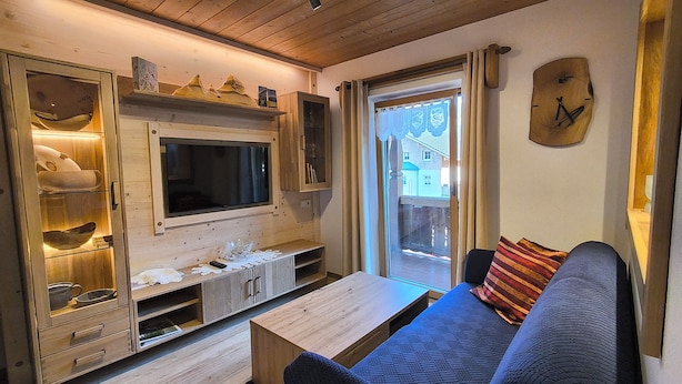 Una sala de estar acogedora con un mueble de televisión de madera, un sofá y una mesa de centro.