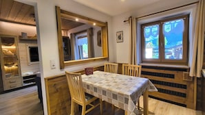 Un comedor con una mesa y sillas de madera, un mantel a cuadros y un espejo grande sobre la mesa.