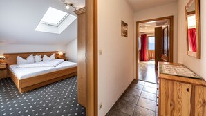 Un dormitorio con tragaluz, cama de madera, mesita de noche y vistas a un balcón a través de una puerta abierta.