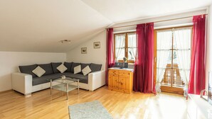 Una sala de estar moderna con un sofá gris, una mesa de centro de vidrio y un mueble de madera.