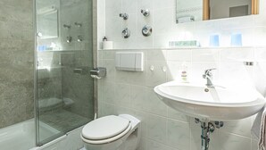 Ein modernes Badezimmer mit einer Duschkabine, Toilette, Waschbecken und Spiegel.