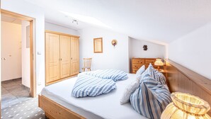 Ein Schlafzimmer mit einem hölzernen Bett, einem Nachttisch, einer Lampe, einem Kleiderschrank und einer Tür.