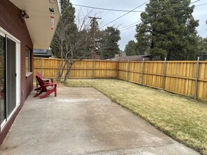 A backyard with a wooden fence, a concrete patio, and a red Adirondack chair. - Flagstaff Hide-a-Way! Walk to downtown! (Flagstaff)