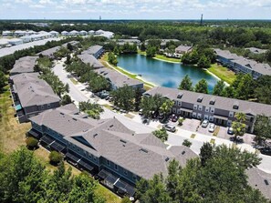 An aerial view of a residential area with multiple buildings, a lake, and surrounding greenery. - Near Disney,Convention Ctr,5br townhome / hot tub/lake view (Kissimmee)