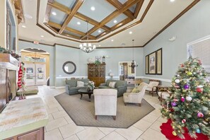 A spacious living room with a high ceiling, a fireplace, a Christmas tree, and a cozy seating area. - Near Disney,Convention Ctr,5br townhome / hot tub/lake view (Kissimmee)