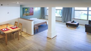 Una habitación moderna con una cama, una mesa de comedor con sillas, un taburete pequeño y un sofá.